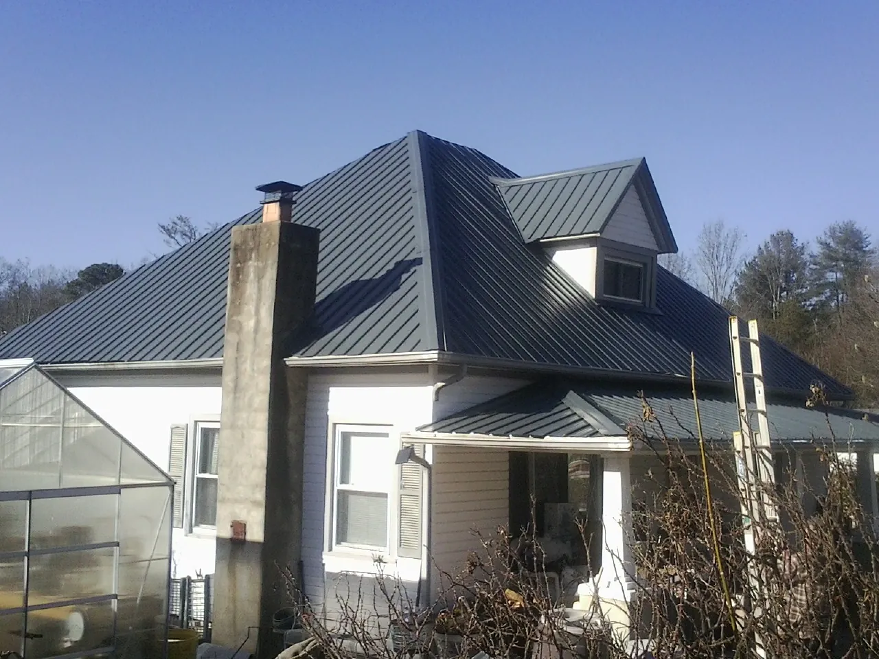 Dark blue standing seam metal roof on a white farmhouse with dormer — Slate & Tile Roof Repair by Roofing Brothers in Richton Park