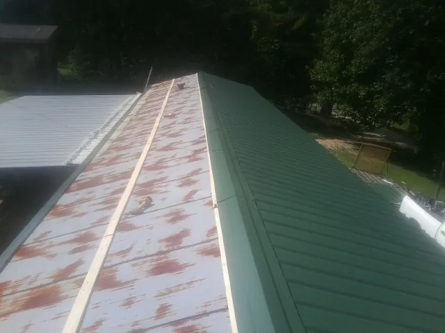 Old rusted panels beside newly installed green metal roofing — Wind Damage Roof Repair by Roofing Brothers in Richton Park