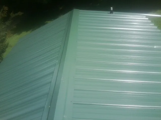 New green metal panels meeting at the ridge of a roof — Flat Roof Repair work by our crew in Richton Park