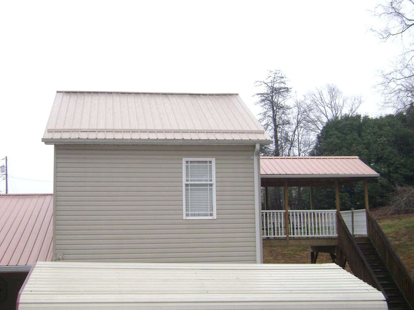Tan metal roofs on a two story addition and attached porch, from a Roof Replacement job in Richton Park