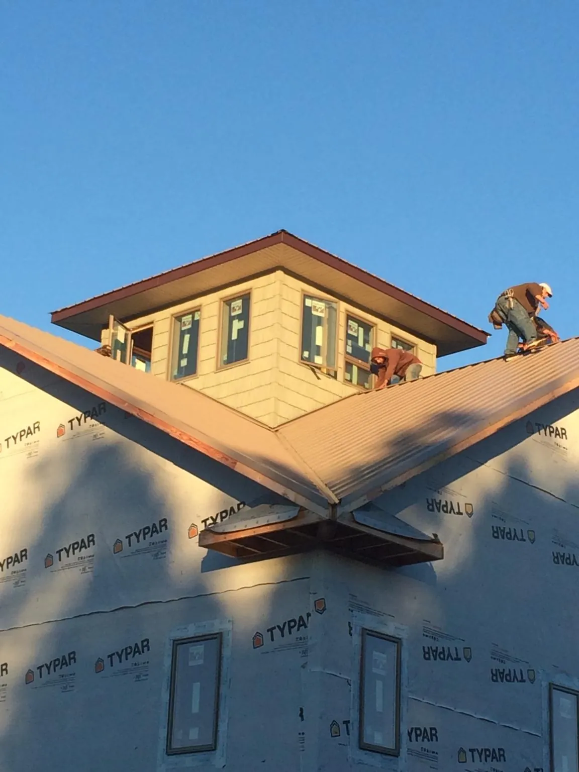 Roofers working around a rooftop cupola on a new metal roof at sunset — Roof Waterproofing in Richton Park by Roofing Brothers